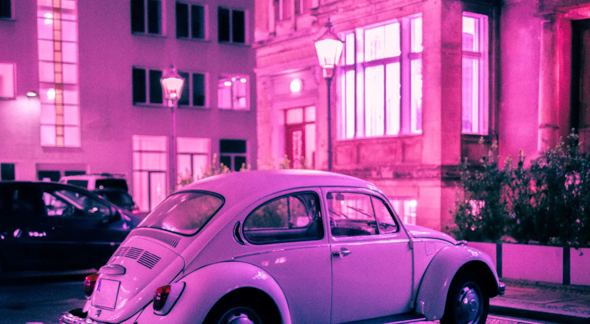 Nächtliche Berliner Straße mit nassem Asphalt und parkendem Oldtimer, stimmungsvoll beleuchtet
